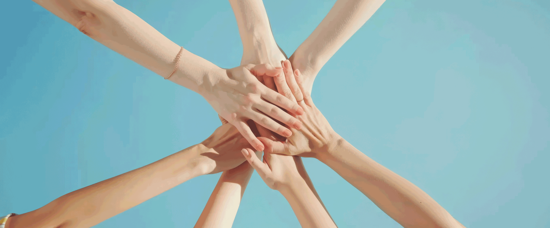 Close-up of hands put together in a gesture of team support and unity on a blue background. Conceptual image representing community, collaboration, teamwork, partnership